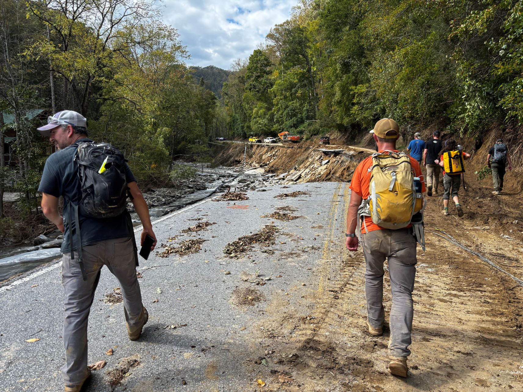 Relief workers walking down a partially washed away road